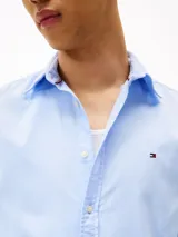 Camisa celeste de corte slim, confeccionada en tejido dobby de algodón con Flex Technology, cuello con botones, puños redondeados con dos botones y logo de Tommy Hilfiger bordado en el pecho.