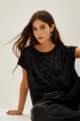 Remera negra de manga corta con lentejuelas, cuello redondo y corte holgado.