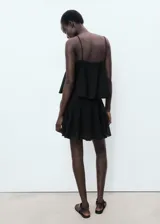 Vestido corto negro de punto fino, sin mangas, con tirantes finos, escote cuadrado y maxi volante superpuesto en el pecho con diseño evasé.