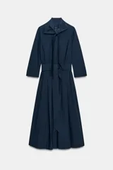 Vestido midi de algodón con cuello con lazada, manga tres cuartos y falda evasé. Incluye cinturón ajustable del mismo tejido y cierre frontal con botones.