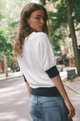 Camiseta de algodón color blanco con cuello redondo, mangas cortas y bajo abullonado, con detalles en color azul marino en el cuello, los puños y el ruedo.