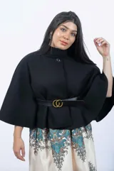 Capa corta negra de paño italiano con cuello alto y cinturón con hebilla dorada.