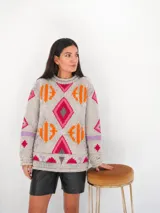 Sweater tejido de punto color gris con diseño geométrico multicolor bordado, cuello redondo y mangas largas.