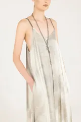 Vestido lencero de satén liviano de viscosa con breteles regulables, degradé hecho a mano y sobreteñido. Presenta escote en V, silueta evasé con vuelo, largo hasta el tobillo, bolsillos laterales, espalda baja en V y ruedo asimétrico.