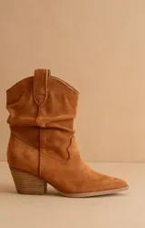 Bota texana de caña media confeccionada en gamuza color suela, con diseño arrugado en el empeine, puntera fina y taco cuadrado de altura media.