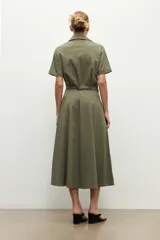 Maxi vestido camisero verde oliva, de manga corta, cuello camisero, cierre frontal con botones, bolsillos con solapa en el pecho, bolsillos laterales y lazo ajustable en la cintura.