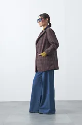 Blazer de corte relajado con estampado de cuadros tipo pied de poule en tonos rojizos y verdes. Presenta solapas clásicas en color azul oscuro y estructura definida.