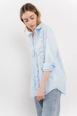 Camisa celeste de algodón liviano con bordado calado tipo broderie, manga larga con puño angosto y botones al frente.