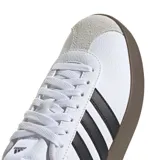 Championes Adidas VL Court 3.0 de estilo urbano, con capellada de cuero sintético blanco, icónicas tres tiras laterales en negro y puntera de gamuza en tono gris claro. Presenta una suela vulcanizada de color marrón oscuro y cierre mediante cordones.