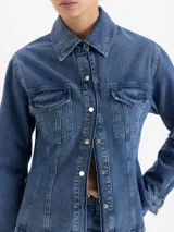Camisa de denim con lavado clásico, corte entallado en la cintura y silueta evasé hacia el ruedo. Presenta cuello camisero, cierre frontal con botones metálicos y dos bolsillos con solapa en el pecho.