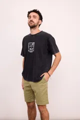 Camiseta de manga corta color negro con efecto gastado (acid wash) y cuello redondo. Presenta un pequeño estampado frontal en blanco con motivos de playa (palmera, sombrilla, reposera).