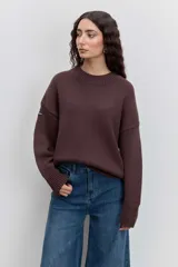 Sweater de punto en color beige, con cuello redondo acanalado, mangas largas con puños ajustados y diseño holgado.