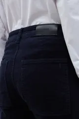 Pantalón de corte recto y tiro alto confeccionado en pana color azul marino. Presenta bolsillos frontales tipo parche y cierre con botón y cremallera.
