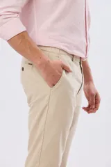 Pantalón de lino color beige, de corte recto y cintura elastizada con presillas para cinturón y bolsillos laterales.