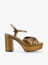 Sandalia de plataforma color bronce metálico con detalle de nudo en la parte delantera y cierre de hebilla en el tobillo. Tiene un taco de 7cm de altura.