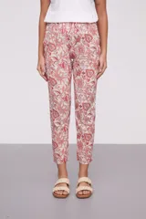 Pantalón de corte recto con estampado floral en tonos coral y verde sobre fondo crudo. Tiene bolsillos laterales y cintura elástica.