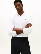 Chomba de manga larga color blanco, con cuello polo y cartera de dos botones. Cuenta con un pequeño logo bordado de Tommy Hilfiger en el pecho y corte regular.