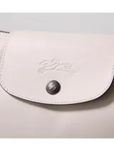 Cartera hobo grande Longchamp de la línea Le Pliage Xtra, confeccionada en cuero color gris claro, con solapa frontal con cierre de botón a presión y correa ajustable para el hombro.