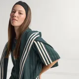 Camiseta de punto oversized verde oscuro de la colección Icons de Adidas, inspirada en los años 80, con rayas diplomáticas blancas, las icónicas tres tiras de la marca en las mangas, cuello redondo y el logotipo del trébol bordado junto al escudo vintage de la Juventus.