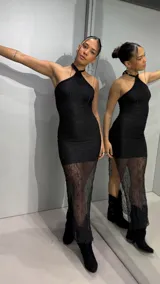 Vestido largo negro con cuello halter, cuerpo ajustado de tela texturizada y falda larga semitransparente de encaje.
