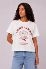 Remera manga corta de algodón color blanco, con cuello redondo y diseño holgado. Cuenta con estampado en el pecho de un paisaje de playa con palmeras en color verde.