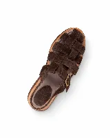 Sandalias de cuero gamuzado color marrón, estilo romano con tiras entrelazadas, suela plana de madera y hebilla metálica lateral.