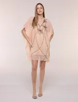 Vestido estilo túnica de dos piezas, color salmón, compuesto por un sobrevestido holgado de gasa semitranslúcida con mangas kimono y escote en V con bordados brillantes de piedras y cuentas, y un vestido base interior tipo enagua de tirantes finos.