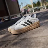 Championes adidas VL Court Bold con diseño de plataforma, capellada de cuero sintético blanco, las icónicas tres tiras laterales en negro y suela de goma color caramelo.