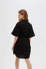Vestido corto de algodón color blanco con diseño de broderie, cuello camisero, cierre frontal con botones, mangas cortas y lazo ajustable en la cintura.