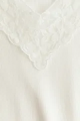 Top entallado de punto acanalado suave, color blanco, de manga corta con escote en V pronunciado ribeteado en encaje.