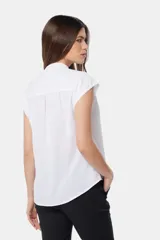 Blusa blanca sin mangas, con cuello mao y cierre frontal oculto con botones.