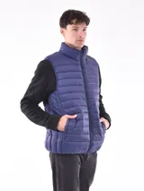 Chaleco acolchado color azul marino, con cuello alto y cierre frontal. Se lleva sobre una prenda de manga larga negra.