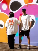 Remerón unisex de algodón color crudo con cuello redondo y estampado en la espalda con la inscripción "DELK BRISHA CLUB" en color naranja.