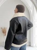 Campera de ecocuero negra con interior de corderito blanco, cierre frontal con cremallera y bolsillos laterales.