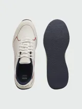 Zapatillas deportivas Boss modelo TTNM EVO, color blanco hueso con detalles en azul marino y ribetes rojos. Presentan una combinación de malla transpirable y paneles de cuero liso con perforaciones. La suela es gruesa y curvada, con detalles en azul marino en la puntera y el talón.