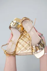 Sandalias bajas doradas con tiras anchas entrecruzadas en dorado y plateado, con pulsera al tobillo y taco cuadrado bajo.