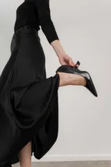 Zapato de tacón negro de cuero, con punta fina y taco con forma geométrica.
