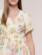 Vestido maxi de gasa color beige con estampado floral en tonos amarillos y rosados, escote en V cruzado, mangas cortas abullonadas y cintura elastizada con nido de abeja.