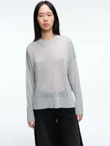 Sweater de tejido fino y semitransparente con hilo brillante. Presenta cuello redondo, hombros caídos y mangas largas amplias con un ajuste relajado y caída fluida.