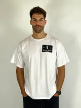 Remera blanca de manga corta con cuello redondo y estampa rectangular negra en el pecho con el logo y nombre de la marca Duxon Jeans.