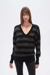 Sweater negro con cuello en V, diseño holgado y mangas largas. Presenta rayas horizontales de lentejuelas plateadas.