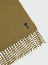 Bufanda de lana en color verde oliva, con diseño liso, flecos en los extremos y pequeño logo de corazón bordado en la parte inferior.
