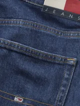 Jeans de mezclilla azul oscuro, corte slim, con cinco bolsillos y cierre de botones. Presenta un pequeño detalle de logo rectangular en el bolsillo delantero derecho.