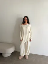 Conjunto gris melange compuesto por un buzo de cuello bote amplio y corte asimétrico con bolsillos, y un pantalón largo de corte recto y holgado.