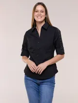 Camisa negra de poplín de algodón, de silueta semi entallada con cuello camisero, escote en V y cartera frontal con botones a presión. Cuenta con mangas 3/4 arremangables con detalle de cinta y argolla metálica, dos bolsillos plaqué en el pecho y paneles laterales elásticos.