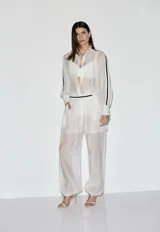 Pantalón Aladdin de mujer color blanco semitransparente, con cintura elastizada y puños fruncidos en los tobillos. Presenta una silueta amplia y fluida con diseño cómodo y relajado.