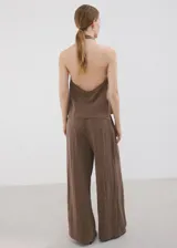 Pantalón de corte recto y tiro regular, color marrón, con bolsillos laterales y traseros con ribete. Cierre frontal con cremallera, botón y ganchos ocultos.