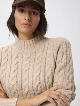 Sweater de tejido grueso con textura trenzada, cuello alto y mangas largas.