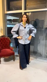 Camisa de algodón color celeste, con silueta relajada, mangas largas abullonadas con puños con volados y cierre frontal con botones de madera.