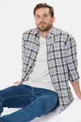 Camisa de lino de manga larga con diseño a cuadros en tonos celeste, beige, azul marino y blanco. Cuenta con cuello camisero, cierre frontal de botones y un bolsillo ojal en el pecho con logo bordado.